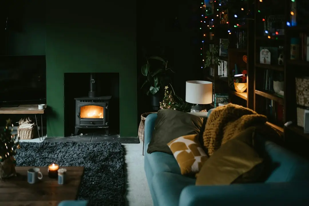 Ett mörkt vardagsrum en kväll med brasa i kaminen, blå soffa och en tv, redo för IPTV i Sverige med Toucan IPTV